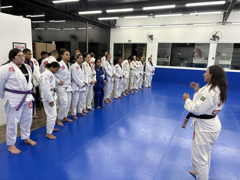 Professora Vanessa Silva conversando com a turma reunida no tatame