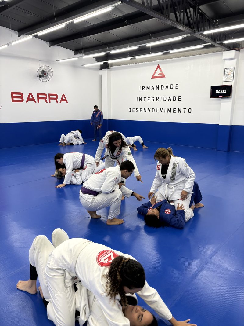 Alunas treinando em duplas no tatame, sob o mural de valores da Gracie Barra