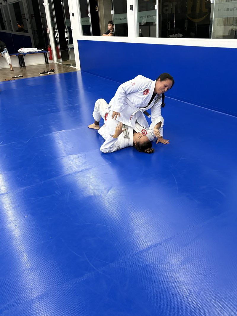 Dupla treinando uma posição no chão, perto da entrada do tatame