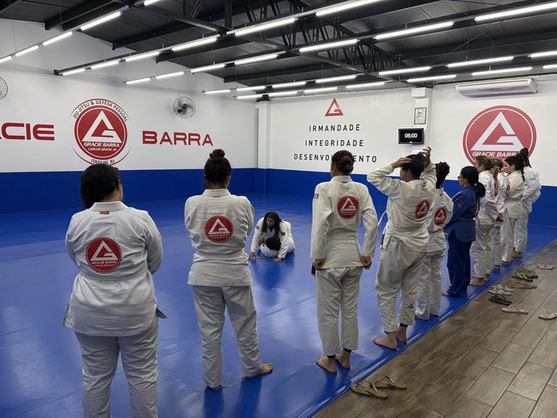 Turma reunida diante do mural com os valores da Gracie Barra: irmandade, integridade, desenvolvimento